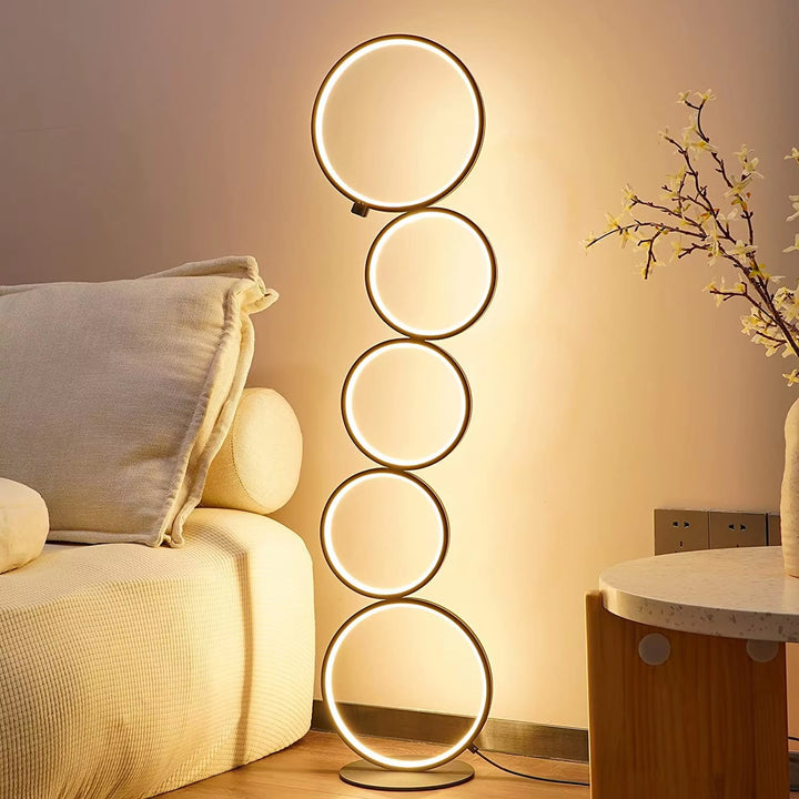 Lampadaire à anneau LED Ihkari éclairant un salon moderne avec lumière blanche chaude
